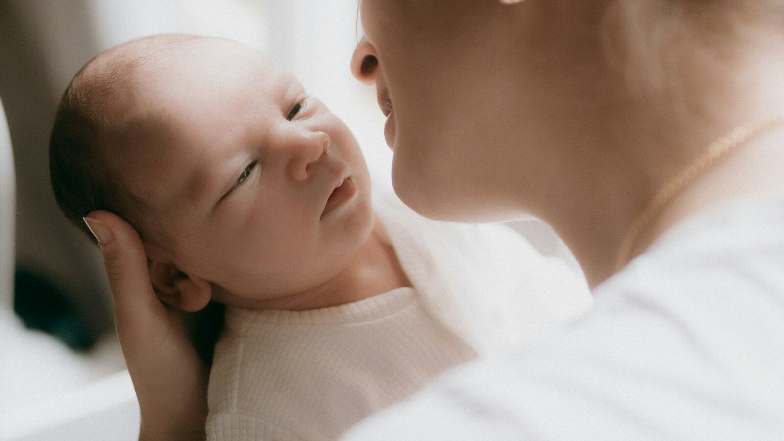 A parent holding a newborn baby in soft morning light at home